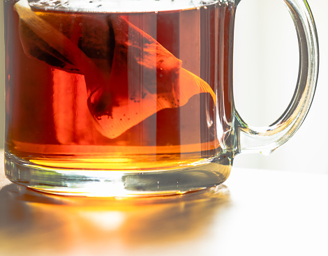 Close-up view of black tea infusion in hot water inside a glass mug. Abstract concept. Healthy lifestyle concept