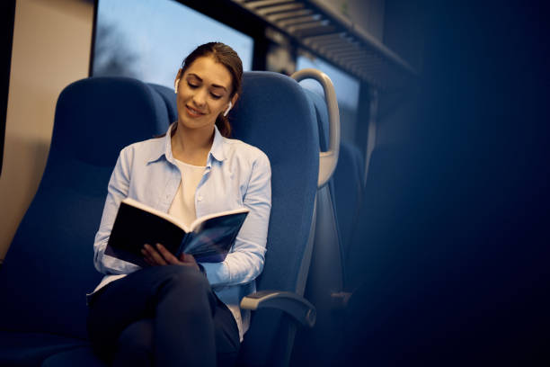 istock Happy woman reading book while traveling by train. 1389547974
