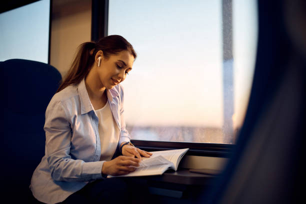 istock Smiling woman reading a novel while commuting by train. 1389549227