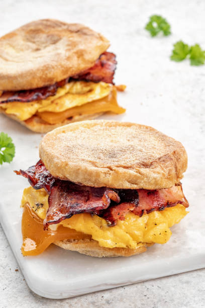 English muffin, egg, ham, and cheese breakfast sandwich on a cutting board