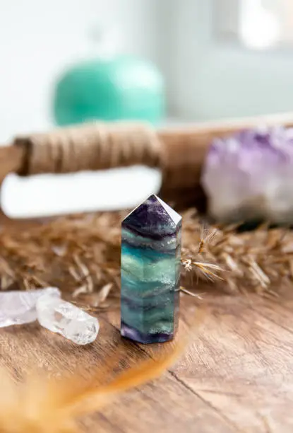 Translucent Fluorite crystal standing point gemstone in home bed room on natural wood tray. Healing and clearing energy concept.