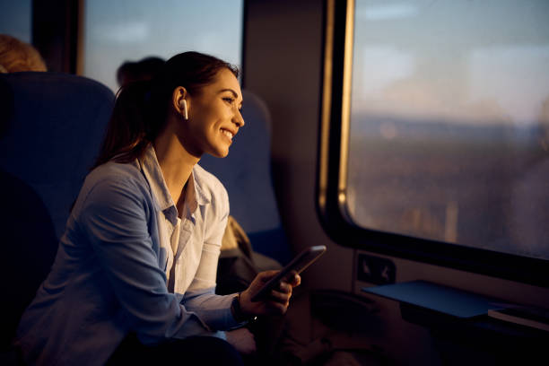 Young happy woman looking through window while traveling by train at sunset.