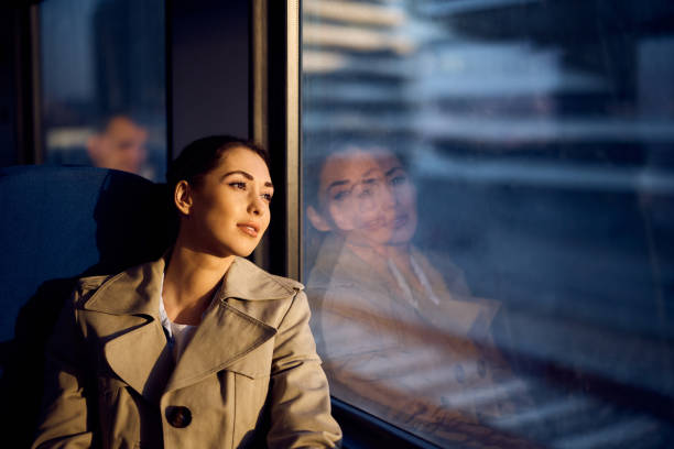 istock Young woman day dreaming by the window while riding in a train at sunset. 1389549460