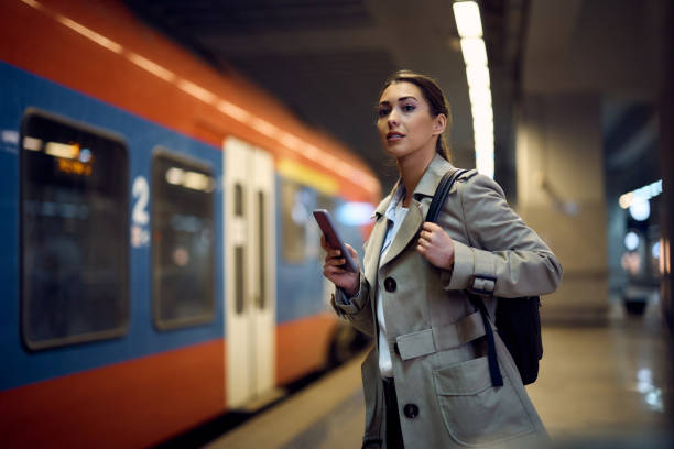 istock Young woman with cell phone at train station. 1389549492