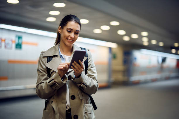 istock Happy woman using smart phone while waiting at train station. 1389549567