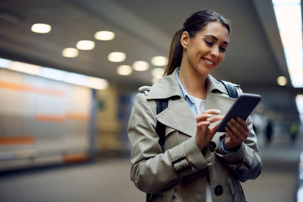 istock Young happy passenger text messaging on her cell phone at subway station. 1389549581