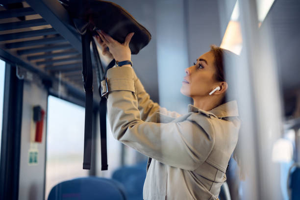 Young passenger putting her bag on the luggage rack in a train.