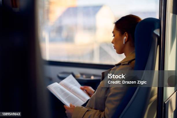 Young Female Passenger Reading Book While Traveling By Train Stock Photo - Download Image Now