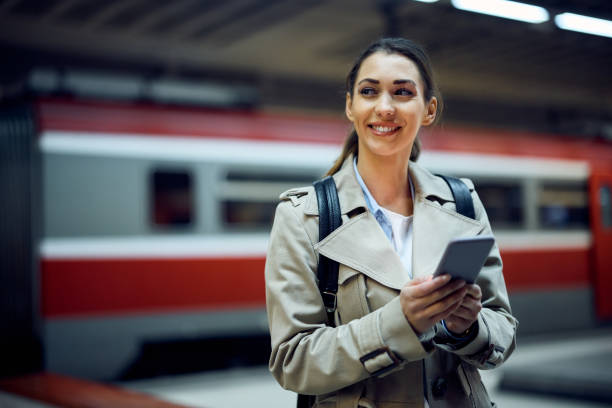 istock Young happy woman using smart phone while arriving at train station. 1389550179
