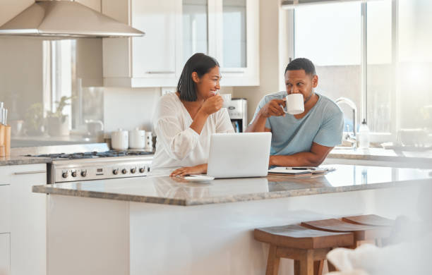 istock Shot of a couple drinking coffee while using a laptop in the kitchen at home 1389558081