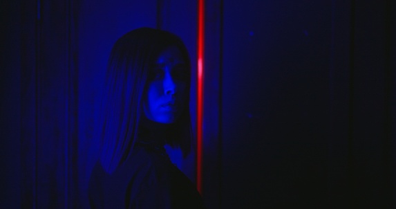 Portrait of Brave cyberpunk girl stands in front of the door in the dark corridor in abandoned building. RGB neon light. Real-time quest attraction