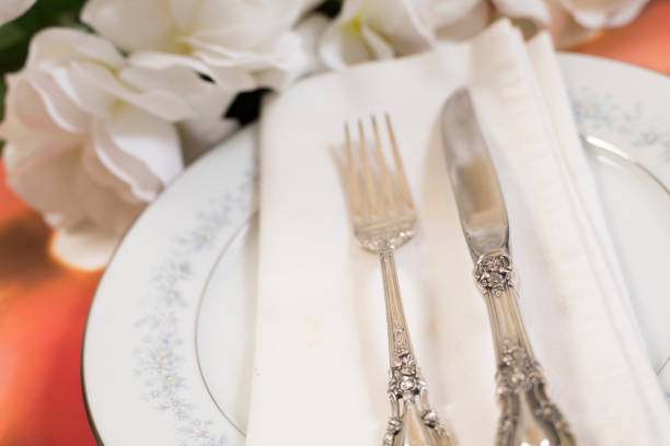 istock Place setting on table with bouquet of white roses. 1389560180
