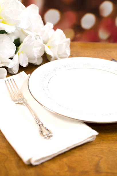 istock Place setting on table with bouquet of white roses. 1389560214