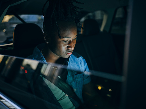 An African American man driving in a car in the downtown area of a city.