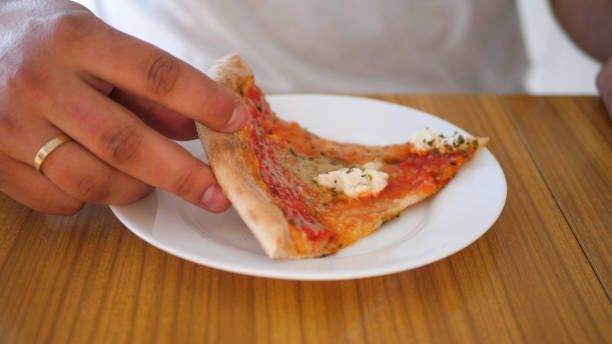 istock Man eating a piece of pizza 1389575174