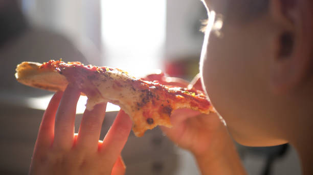 istock Kid eating a slice of pizza 1389575187