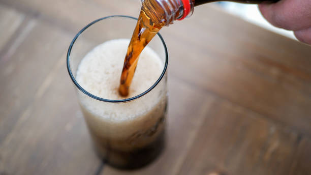 istock Pouring a brown sparkling drink into a high glass 1389575222