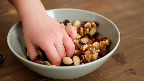 Hands of a kid taking helthy snacks from a bowl