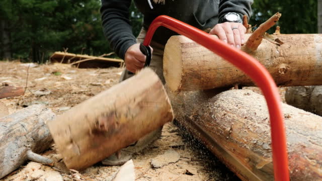 People using a hand saw to cut a piece of wood the old way stock video