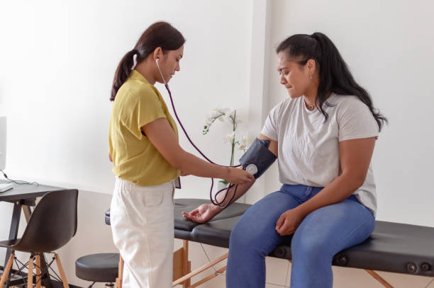 Woman having blood pressure measured by doctor stock photo