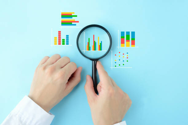 istock Business man's hand with magnifying glass and various business graphs on light blue background 1389582855