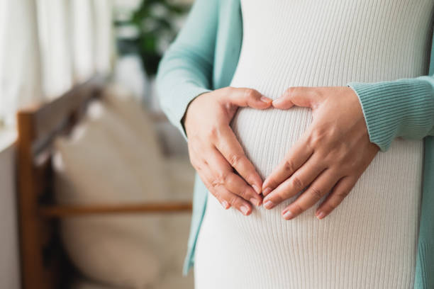 schwangere frau macht herz auf großem bauch - schwanger stock-fotos und bilder