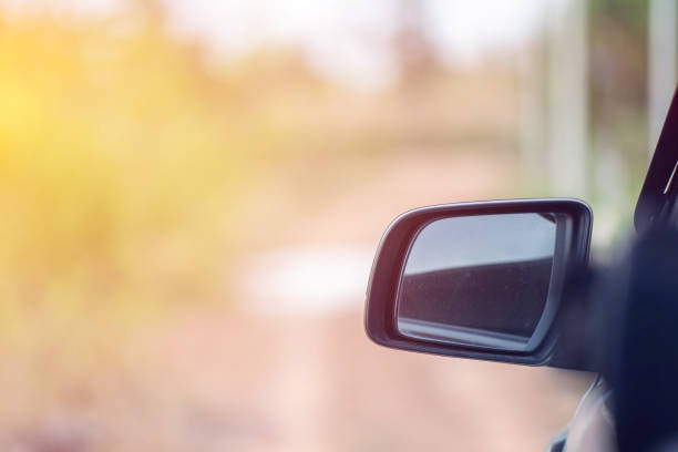 coche conduciendo en la carretera. reflejo de desenfoque en el espejo de un automóvil. reflejo del espejo retrovisor. primer plano del espejo del automóvil con reflejo de detrás del automóvil. - rear view mirror car mirror sun fotografías e imágenes de stock