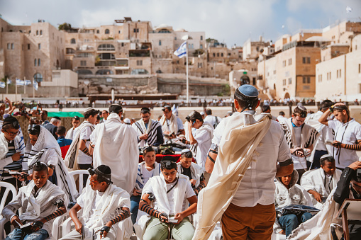 Jerusalem, Israel- April 30, 2022: Jewish gather around at the Western Wall, the most sacred site in Judaism to celebrate the Bar Mitzvah, which is celebrated with friends and family members singing to honor the teenager.