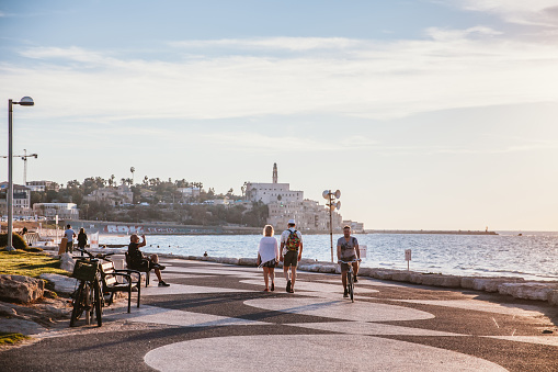 Tel Aviv, Israel, April 29 2022: Locals and tourists walking on street and seaside enjoying the sunshine and laid-back lifestyle in Tel Aviv, which is the most east part of Mediterrean Sea.