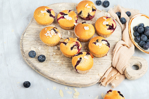 Muffin with blueberries on a wooden plate. Fresh berries and sweet pastries on white background, top view with copy space.