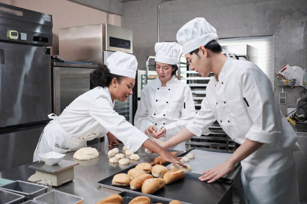 istock Chefs team in uniforms prepare to bake bread and pastry in stainless kitchen. 1389610235