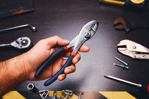 Metal pliers isolated on the mechanic hand with a mechanic tools background