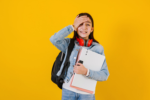 portrait of young hispanic child teen girl student with worried expression on a yellow background in Mexico Latin America