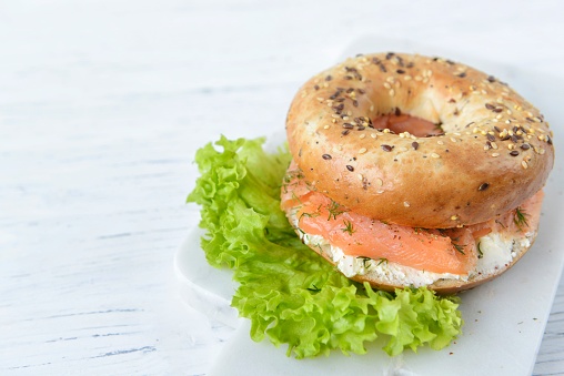 Multigrain bagel with cream cheese, salmon slices, dill and salad