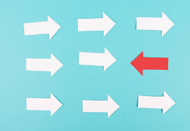 istock White arrows on a blue background, one red is standing out, do different, be a winner, individuality, making your own decision, leadership, target new idea 1389624973