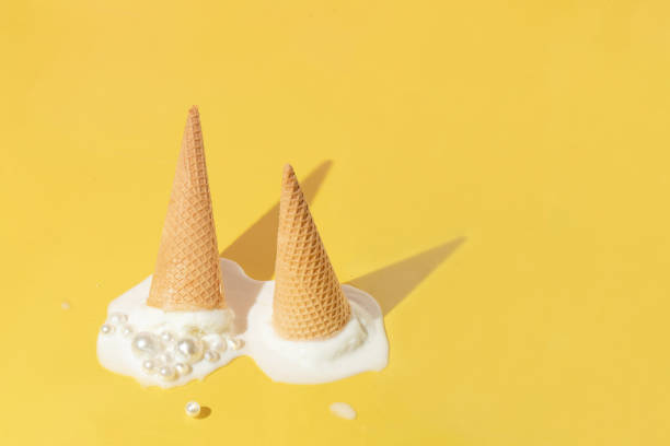 istock Creative layout with two ice cream cones up side down and vanilla ice cream scoops with pearls on bright yellow background. Summer aesthetic idea. Trendy food lay out. 1389627430