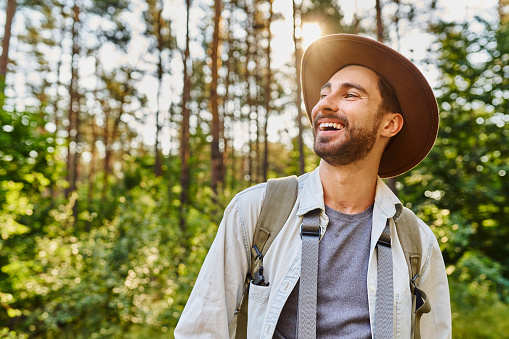 Portrait of happy young man backpacking in forest during summer hike