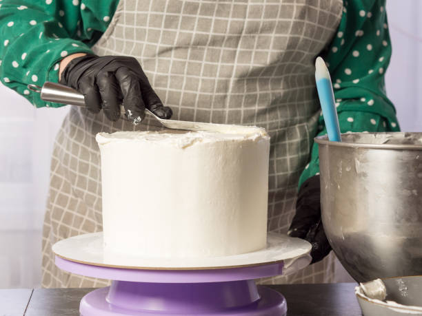 istock the pastry chef makes a white cream cake using a spatula.align the edges of the cake 1389628672