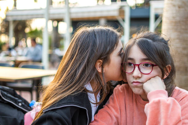 istock Beautiful little girls whispering 1389629915