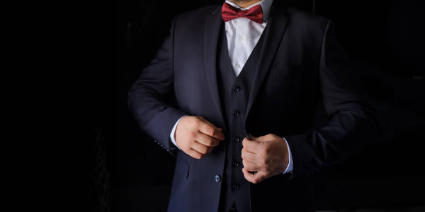 istock man in a suit with red bow on a black background. 1389630303