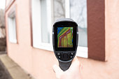 istock A male hand holds a thermal imager at the window of a house. Search for heat loss in private houses 1389631848