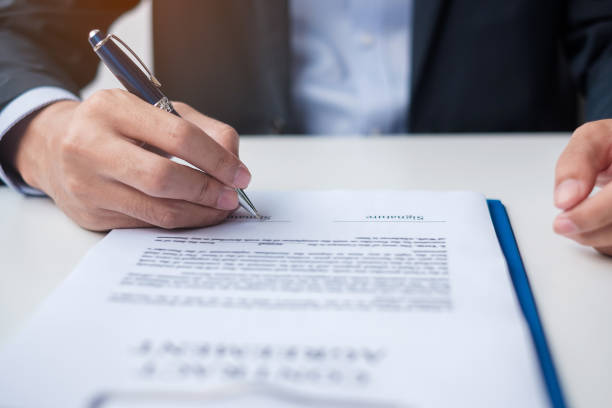 istock man signing on contract documents after reading, man holding pen and approve on business report. Contract agreement, law and deal concepts 1389631896