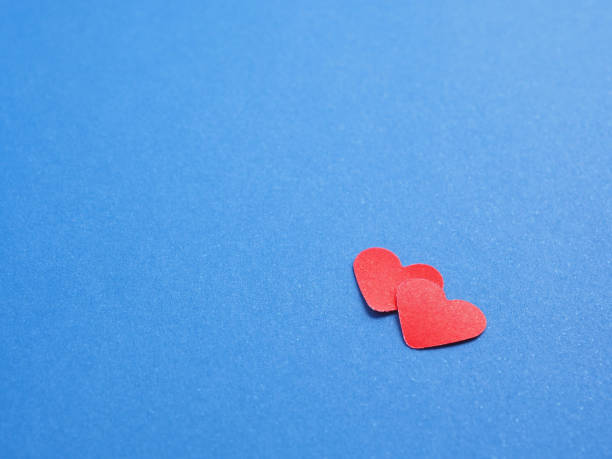 istock Two red hearts on blue paper background. There is space to put text, the concept for design. Close up, copy space. 1389636574