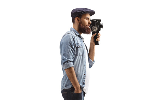 Bearded man recording with a vintage camera isolated on white background