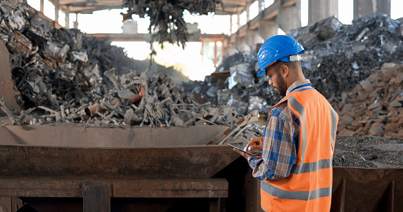 Male engineer standing and inspecting scrap in scrap yard.