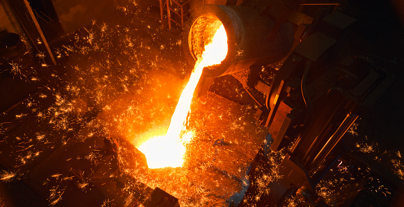 Pouring molten metal to molding system to produce castings in steel mill.