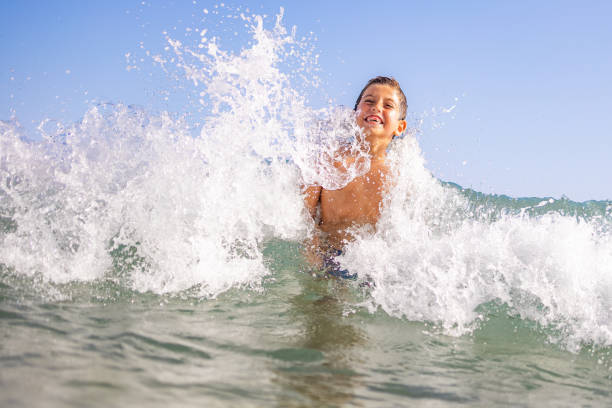 istock Funny kid playing with waves on the beach 1389640547