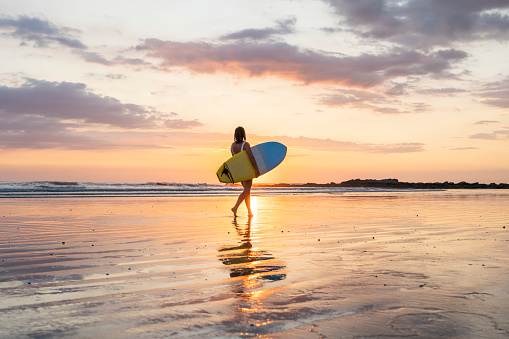 Silueta de chica surfista en la playa al atardecer photo