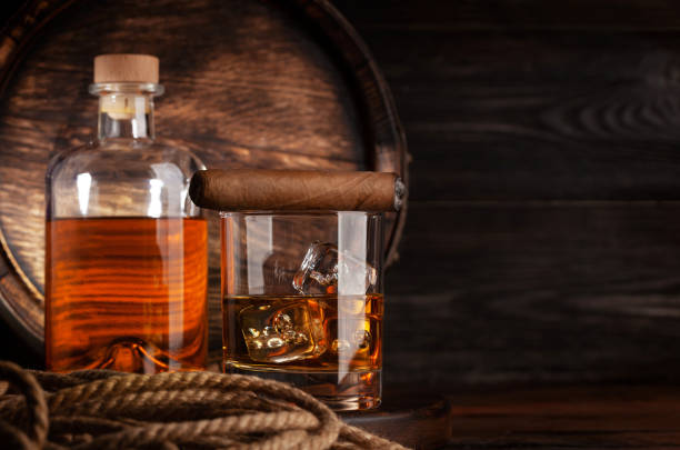 Glass and bottle with cognac Glass and bottle with cognac, whiskey or golden rum. In front of old wooden barrel with copy space glass of bourbon stock pictures, royalty-free photos & images