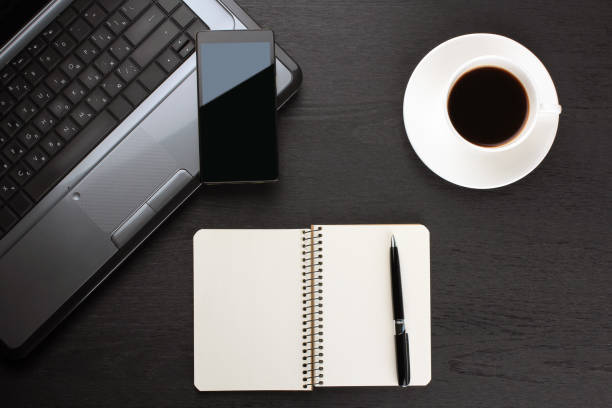 Gadgets and notepad on a black wooden background. Workplace.